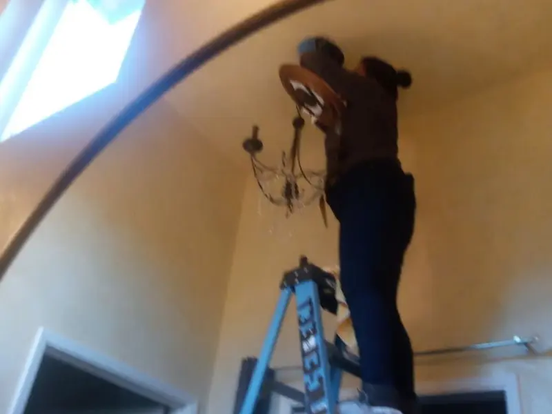 Electrician installing a chandelier in a Lomita residence